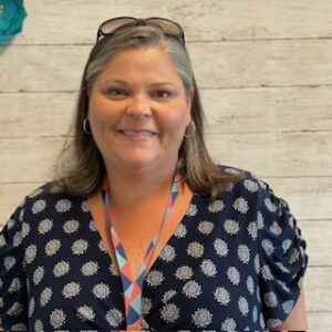 Picture student support coordinator, smiling and standing in front of a wall