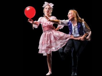 picture of two people, one in pink dress holding a balloon, the other reaching for the balloon